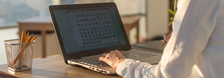 Image of a modern desk setup with a laptop, pencil holder, and natural light, suggesting productivity and digital work.